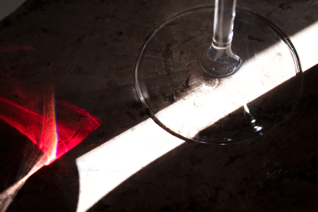 Close-up of a crystal-clear wine glass catching sunlight on a wooden table.