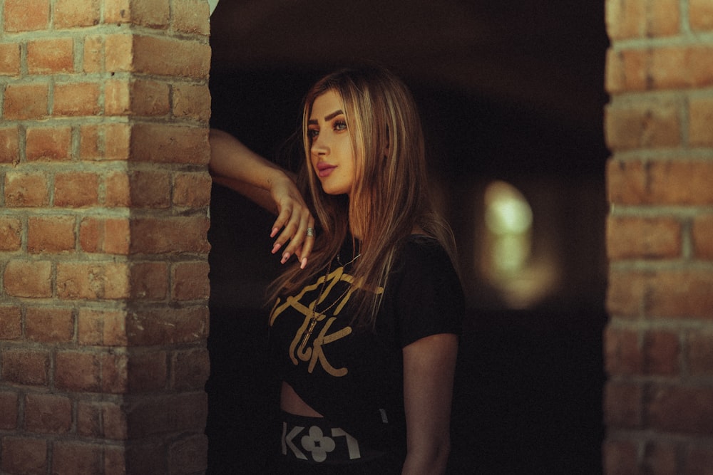 a woman standing in front of a brick wall