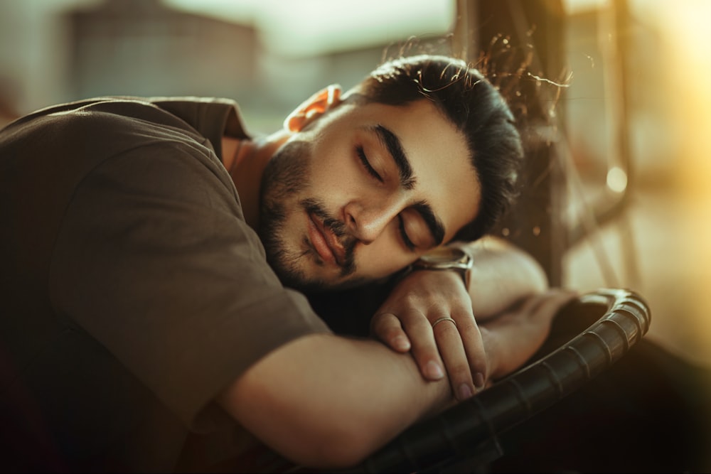 a man sleeping on a bench with his eyes closed