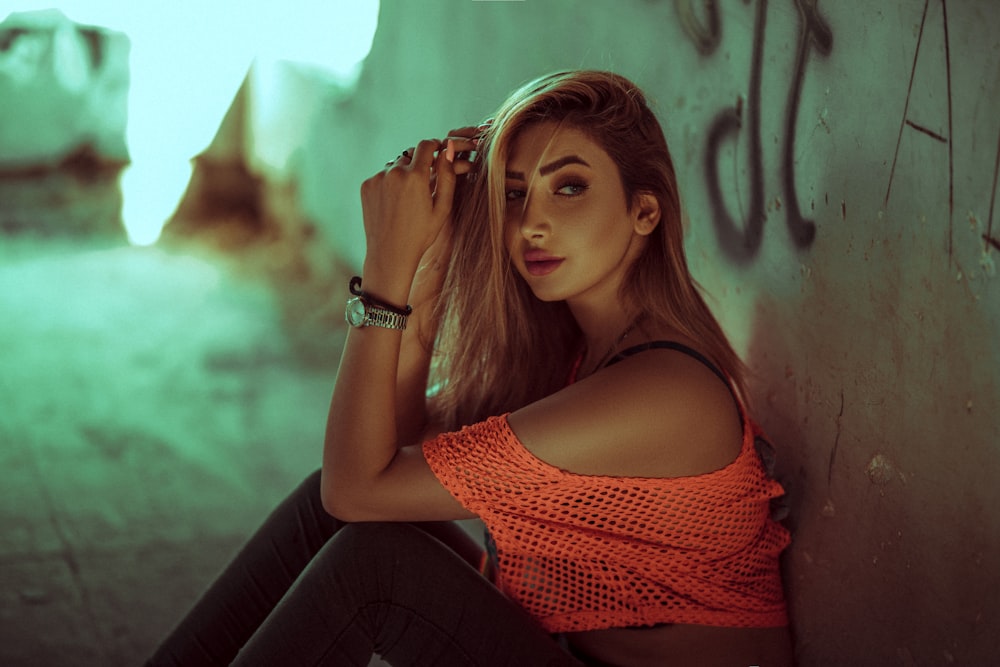 a woman sitting against a wall with her hand on her head