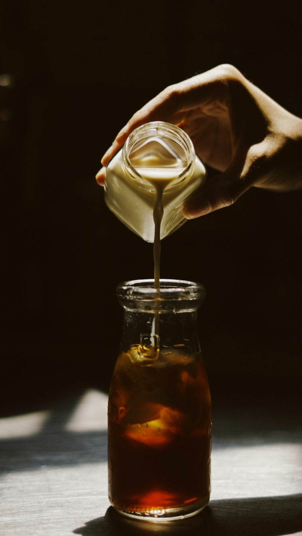 a person pouring a liquid into a glass jar