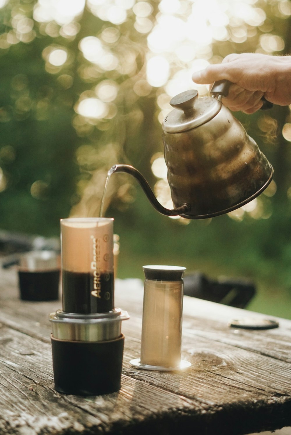 a person pours a cup of coffee from a kettle