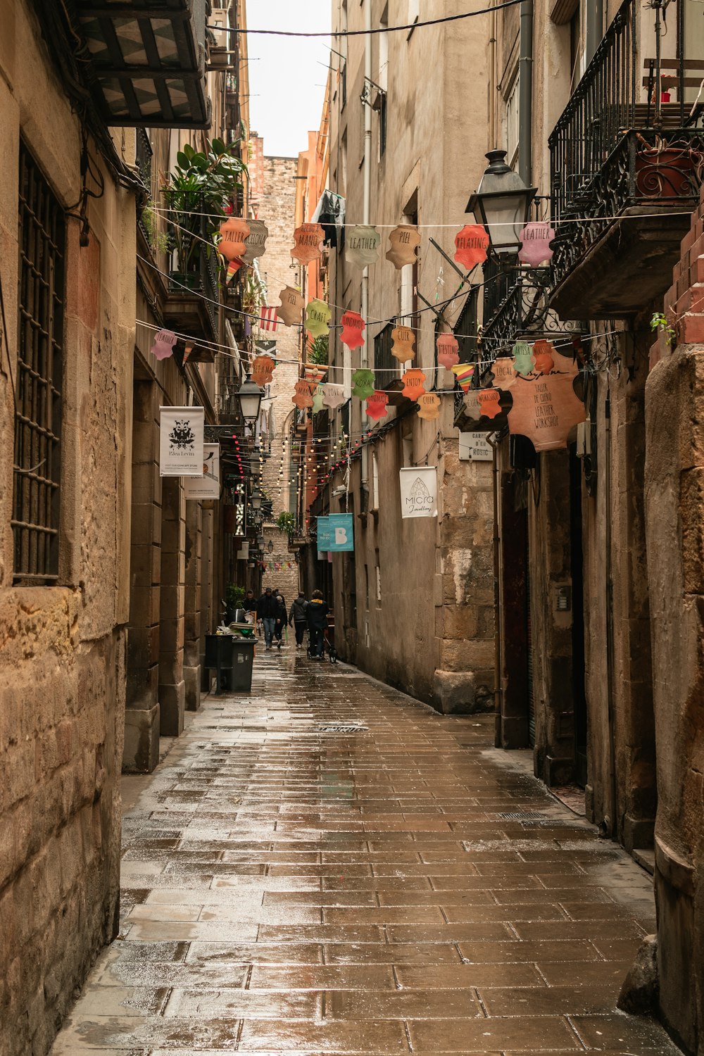 a narrow city street with a few people walking down it