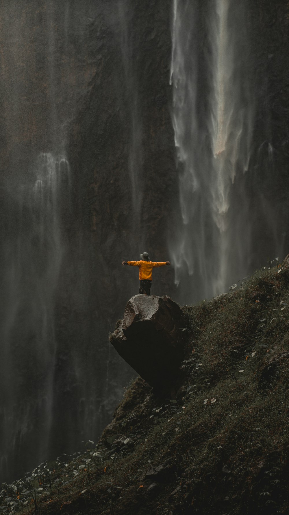 uma pessoa em pé em uma rocha na frente de uma cachoeira