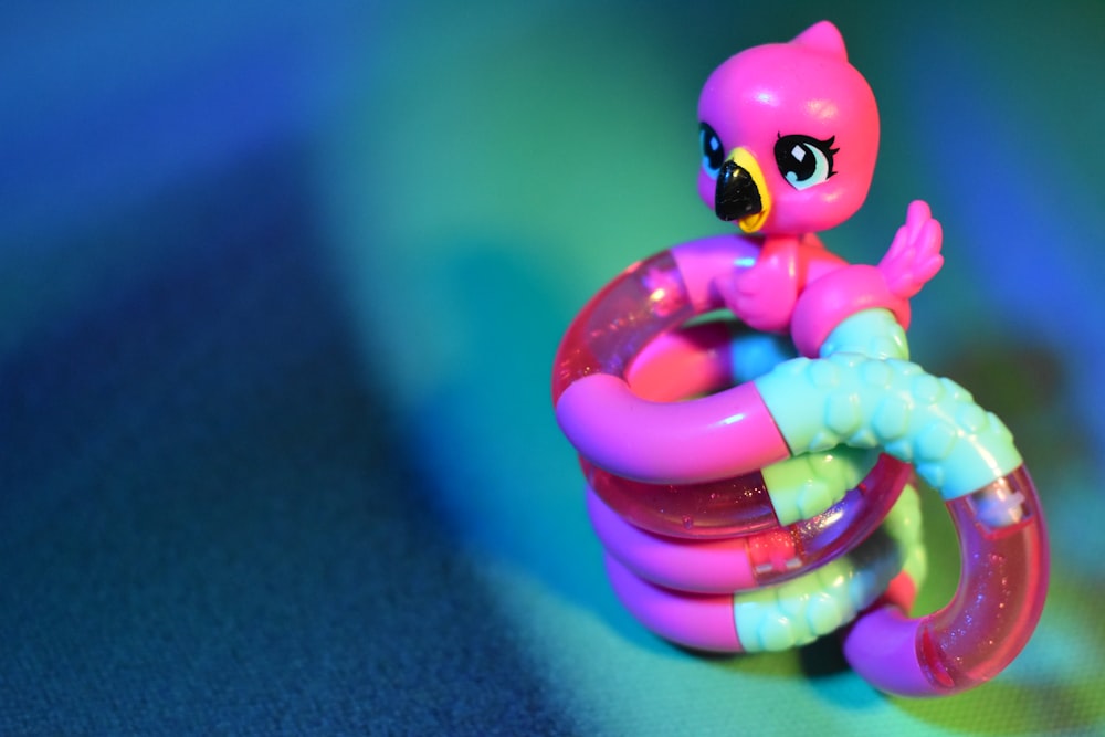 a little pink toy sitting on top of a plastic tube