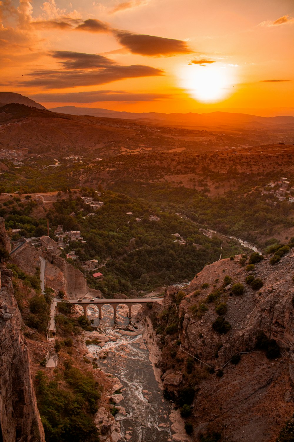 the sun is setting over a canyon with a bridge