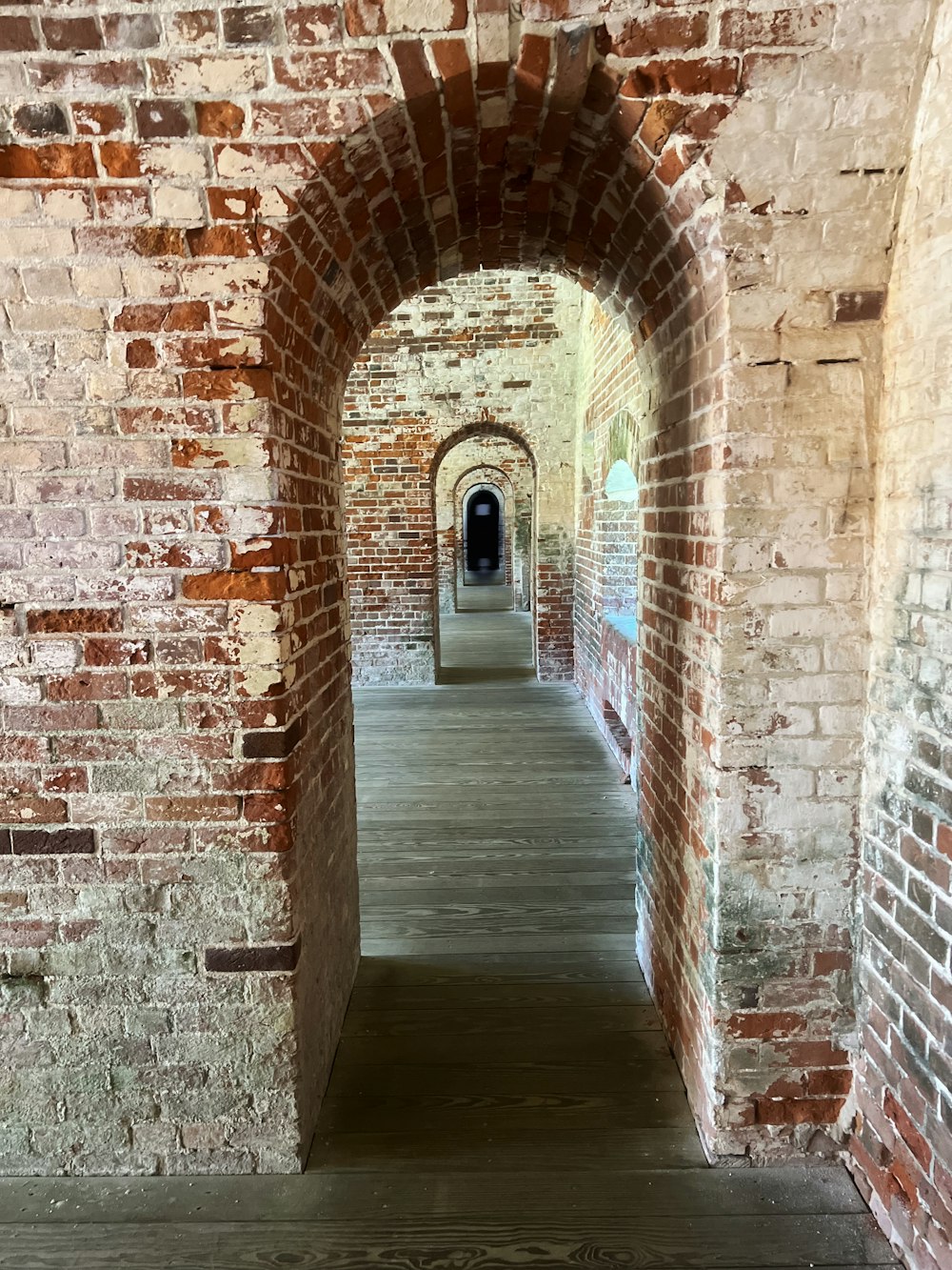 a brick tunnel with a door leading to another tunnel