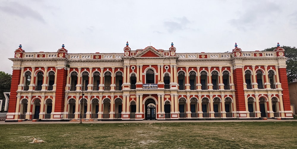 a large red and white building sitting on top of a lush green field