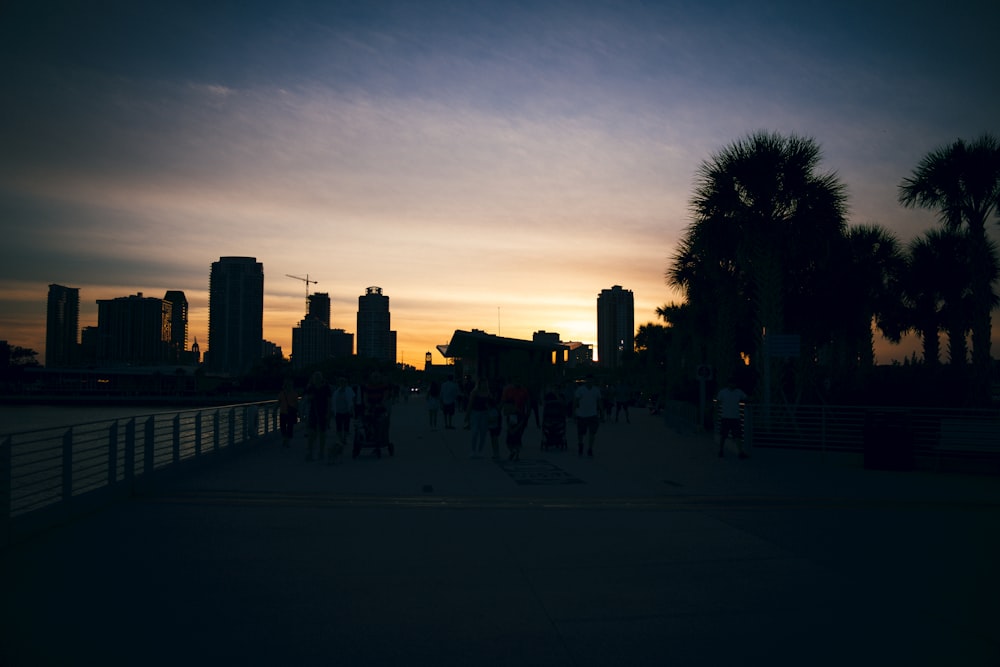 a group of people walking across a bridge at sunset