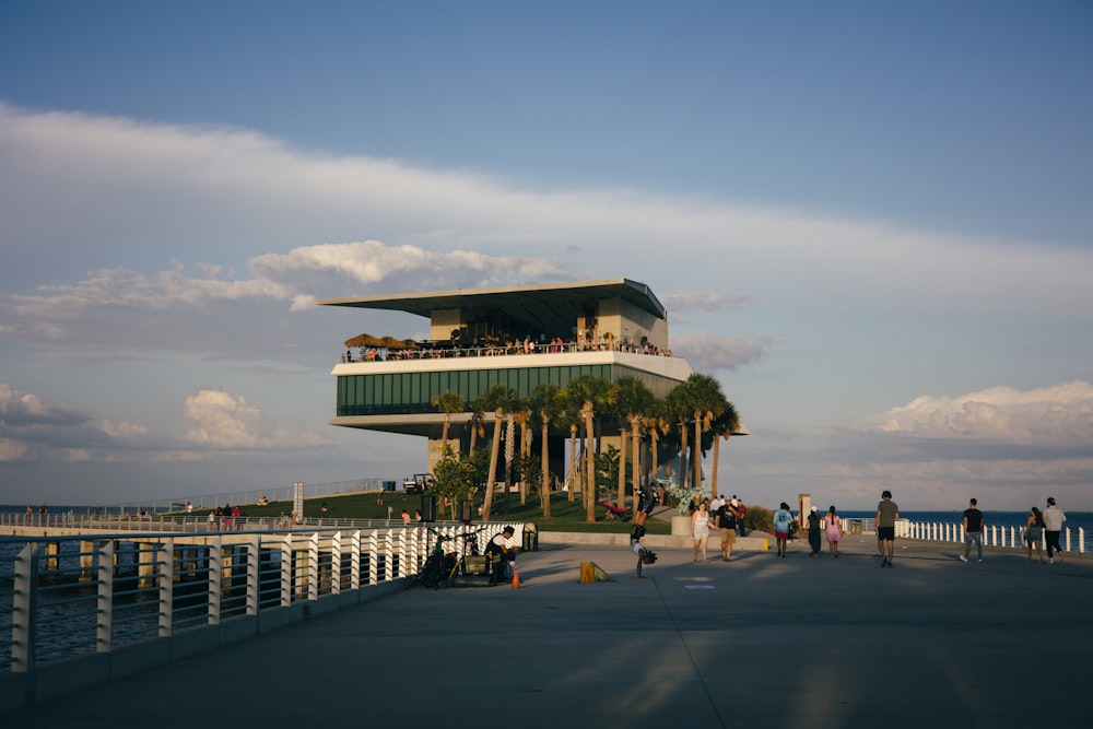 a group of people standing on a pier next to the ocean