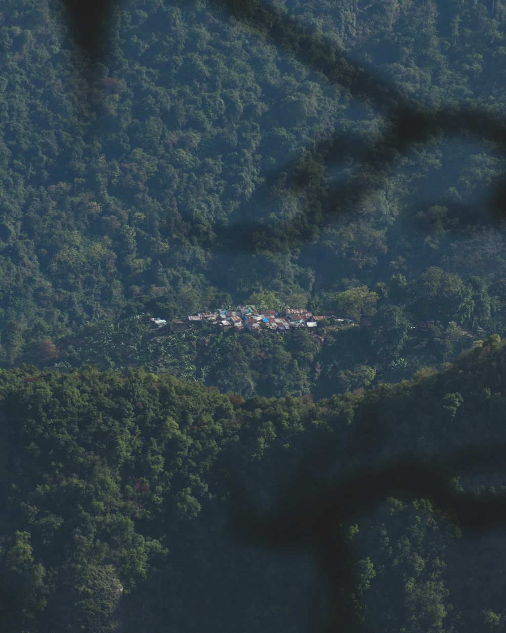 a plane flying over a lush green forest covered hillside