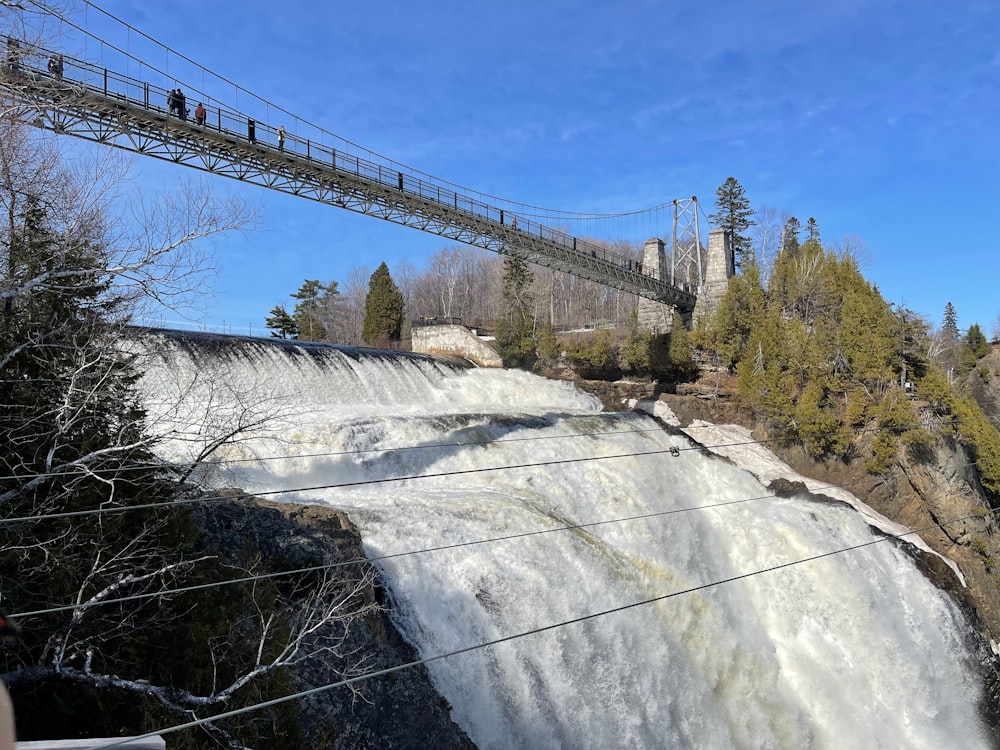 a suspension bridge over a waterfall with people standing on it