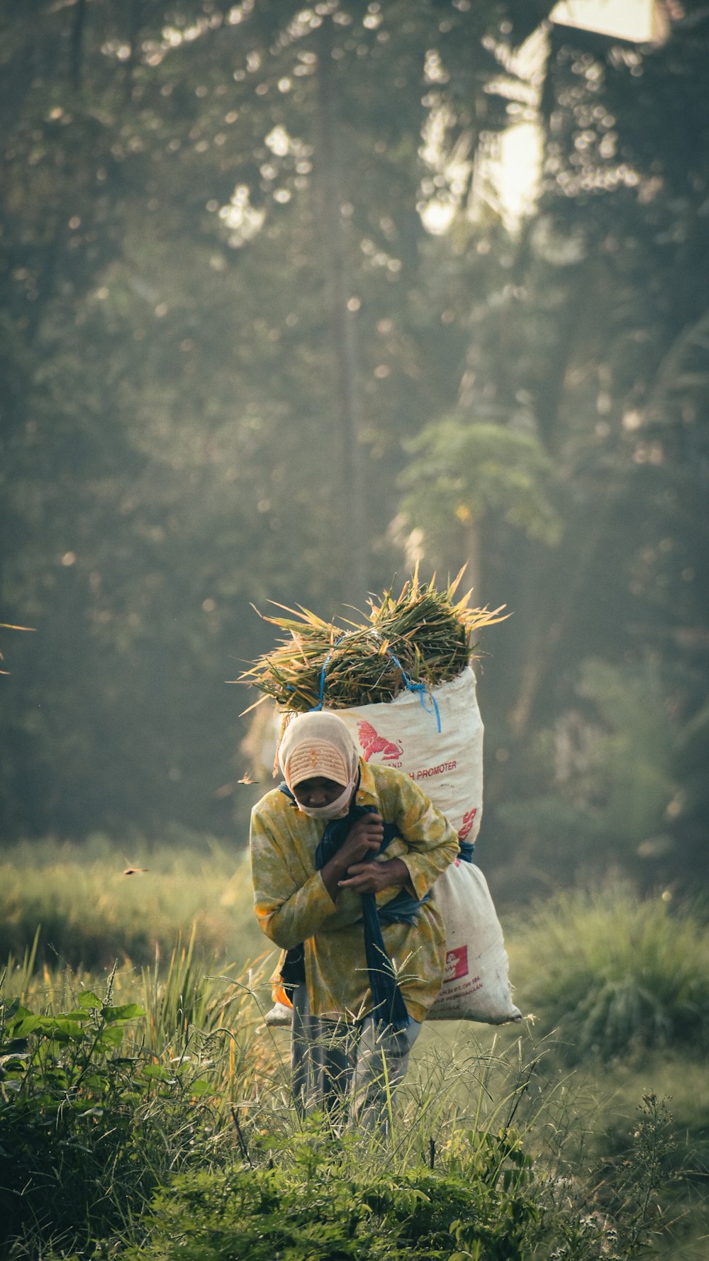 a person carrying a bag of hay in a field