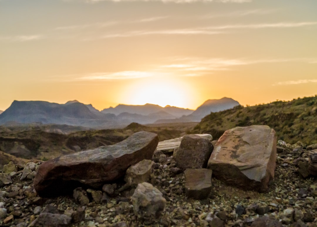 the sun is setting over the mountains and rocks, The rising sun glows as it ascends beyond the horizon at Big Bend Natio