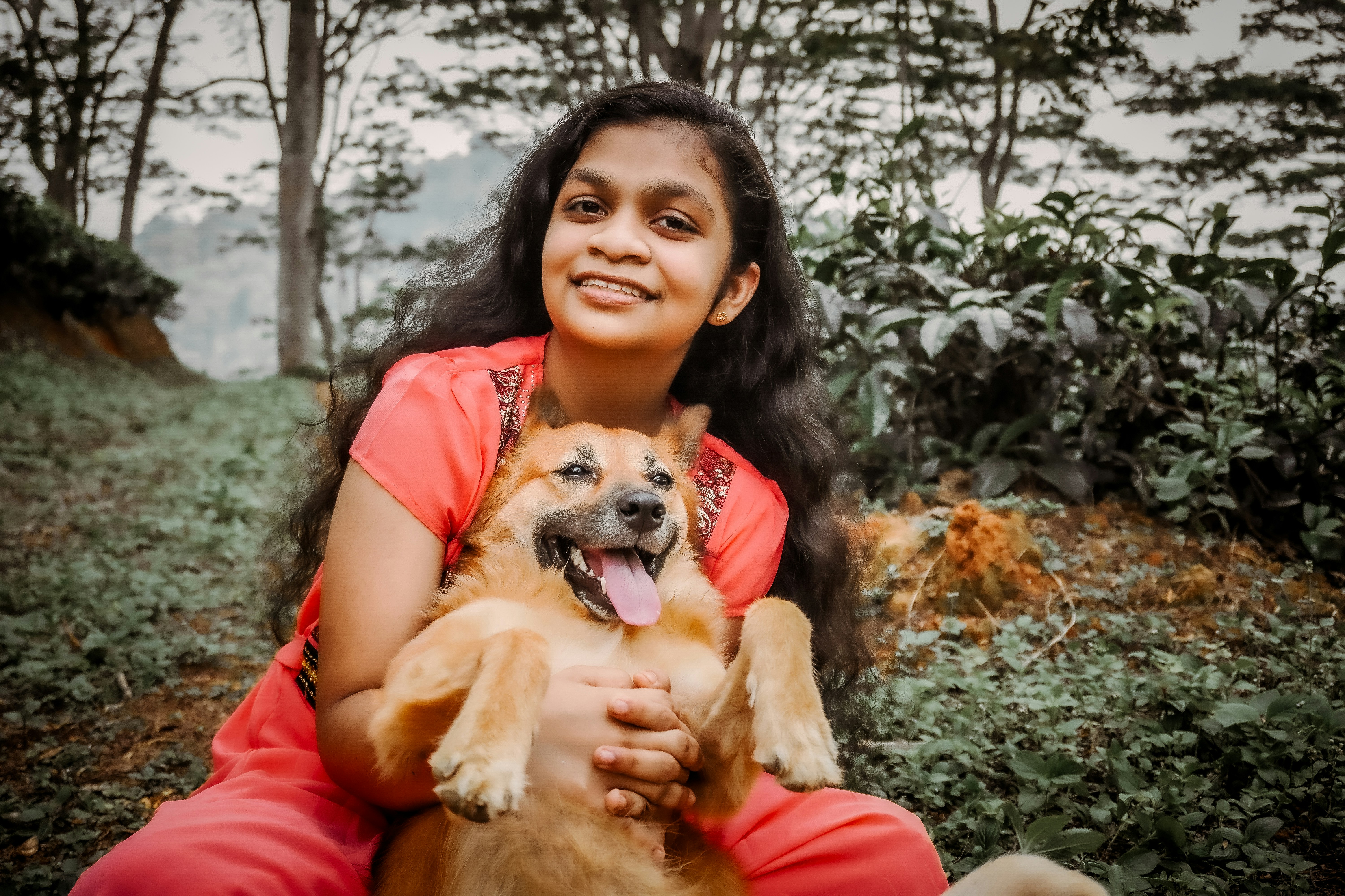 a woman sitting on the ground holding a dog