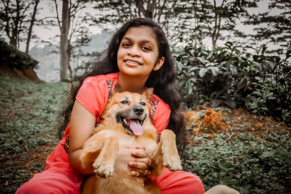 a woman sitting on the ground holding a dog