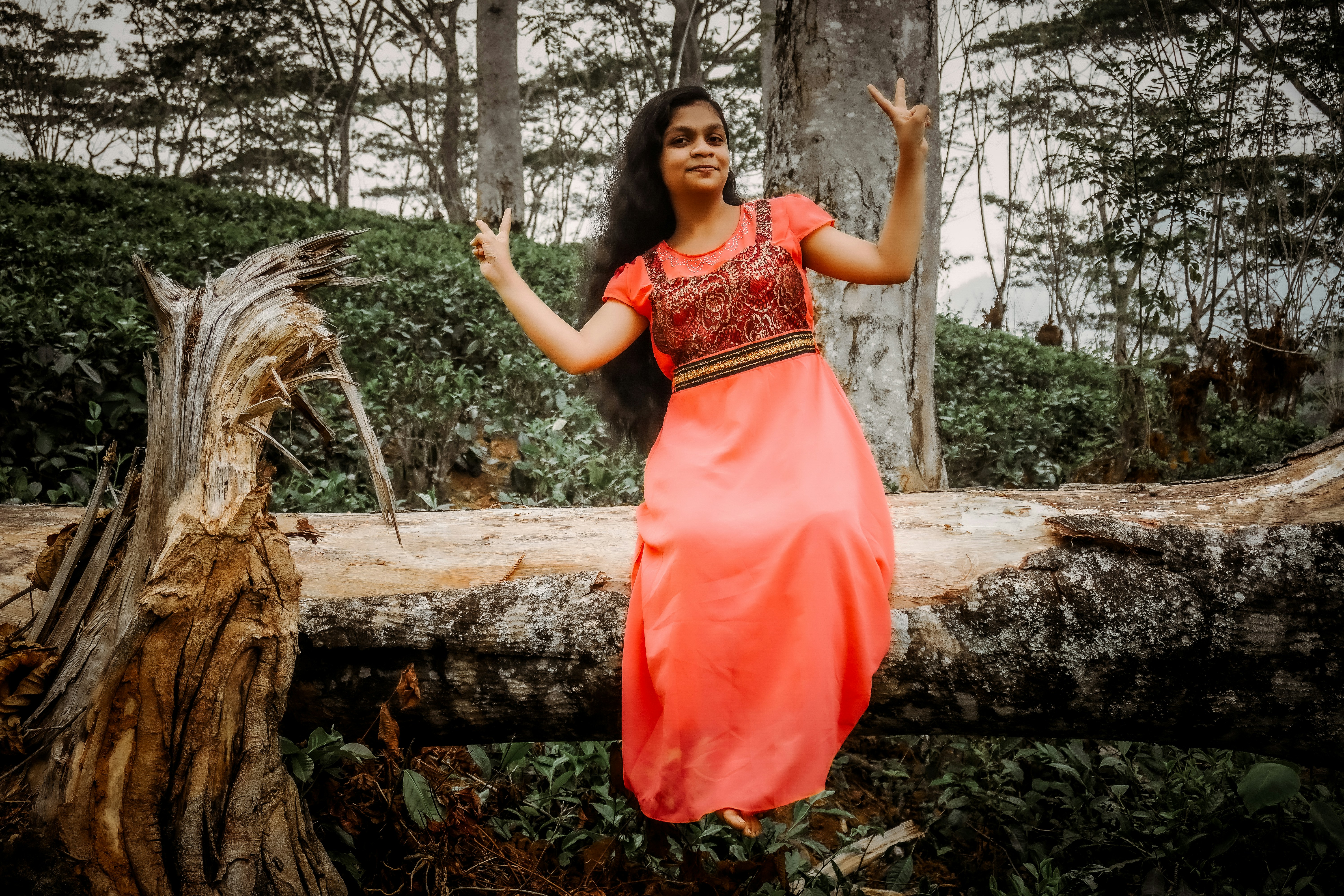 uma mulher em um vestido laranja em pé em um tronco