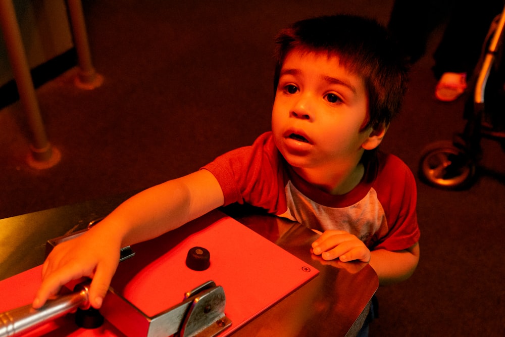 a young boy sitting at a table with a pizza cutter