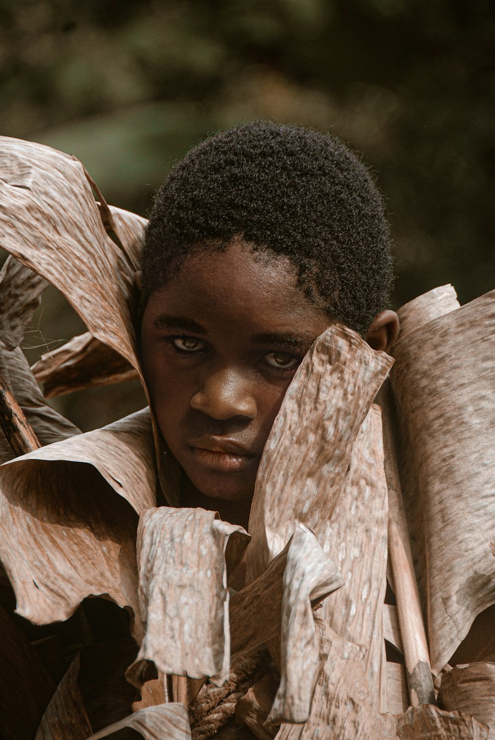 a young boy is hiding behind a large piece of wood