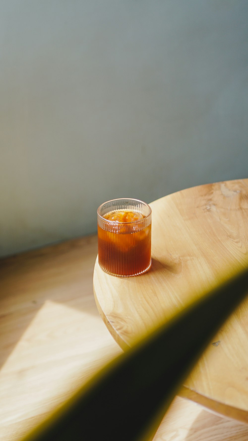 a glass of orange juice sitting on top of a wooden table