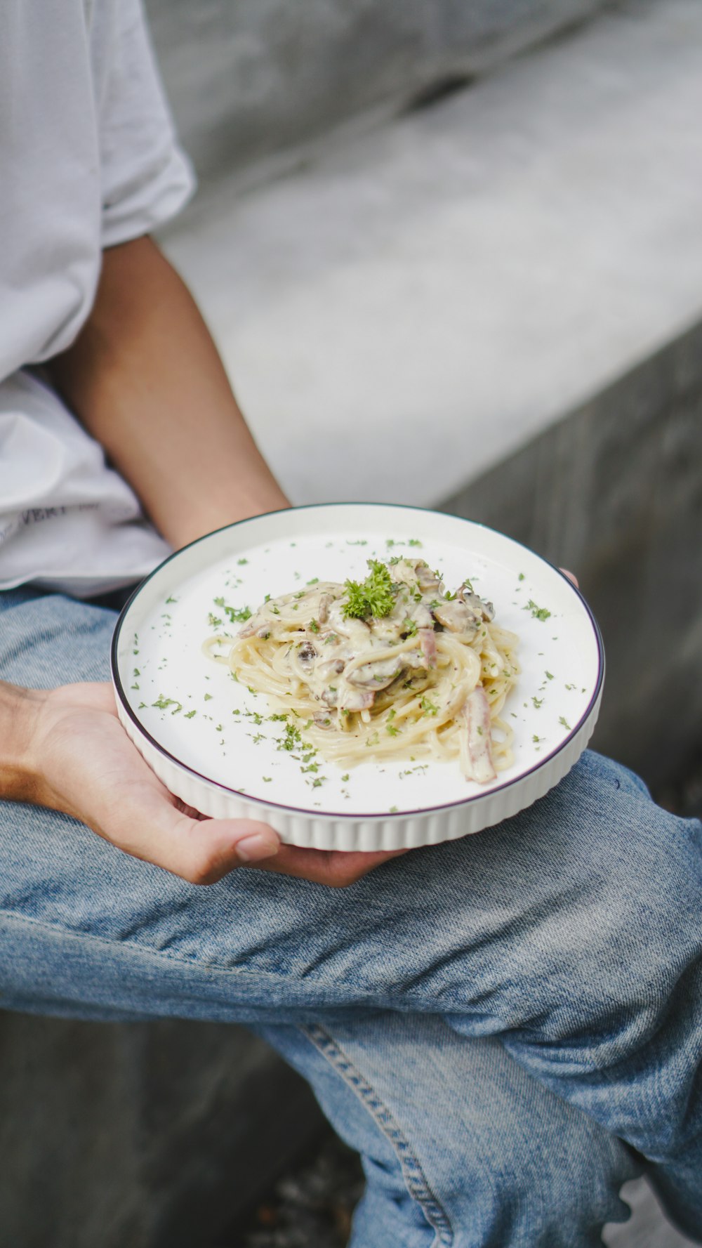 eine Person, die einen Teller mit Essen auf einer Bank hält