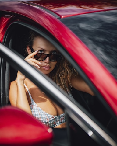 a woman sitting in a red car looking out the window