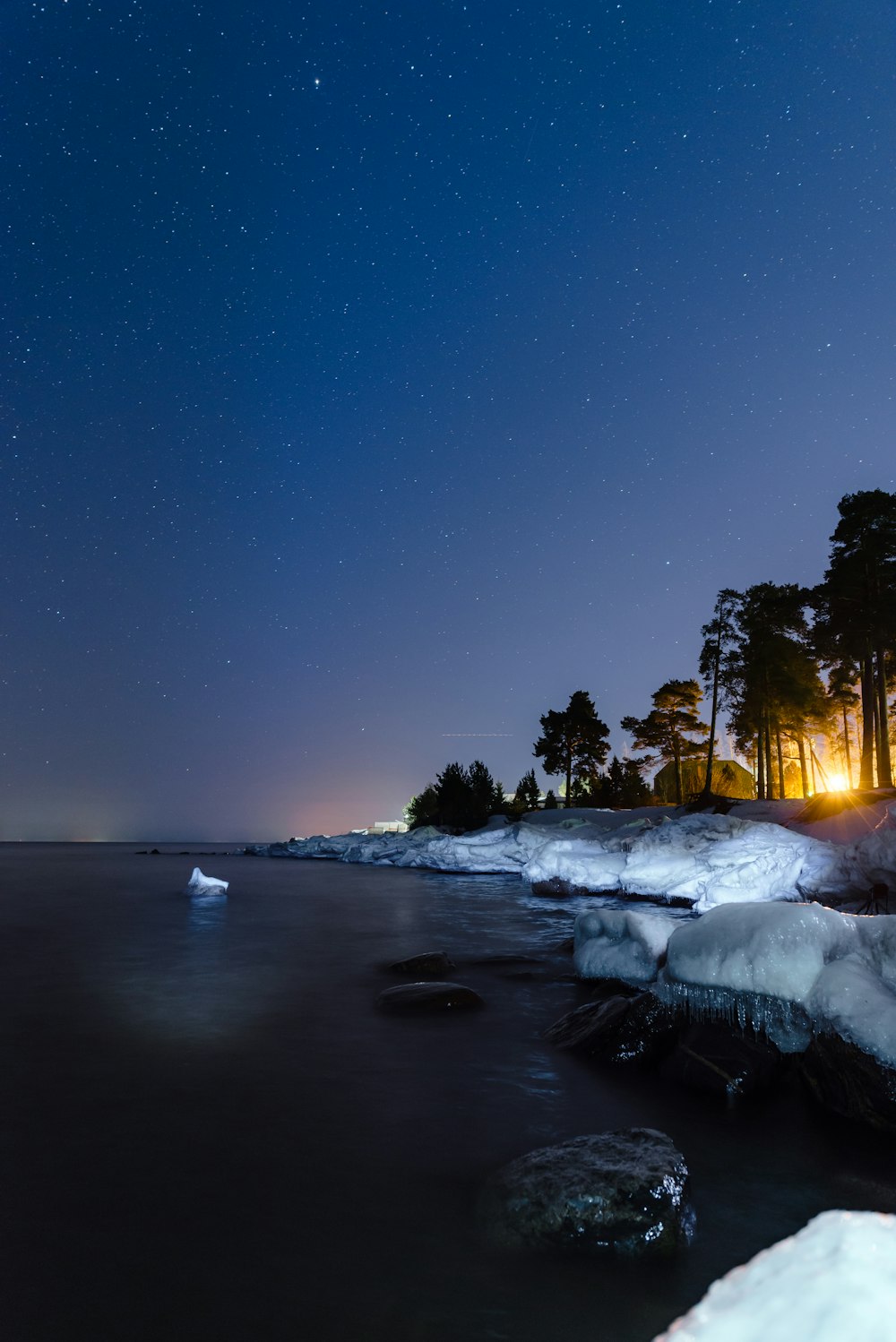 the night sky is lit up over the water