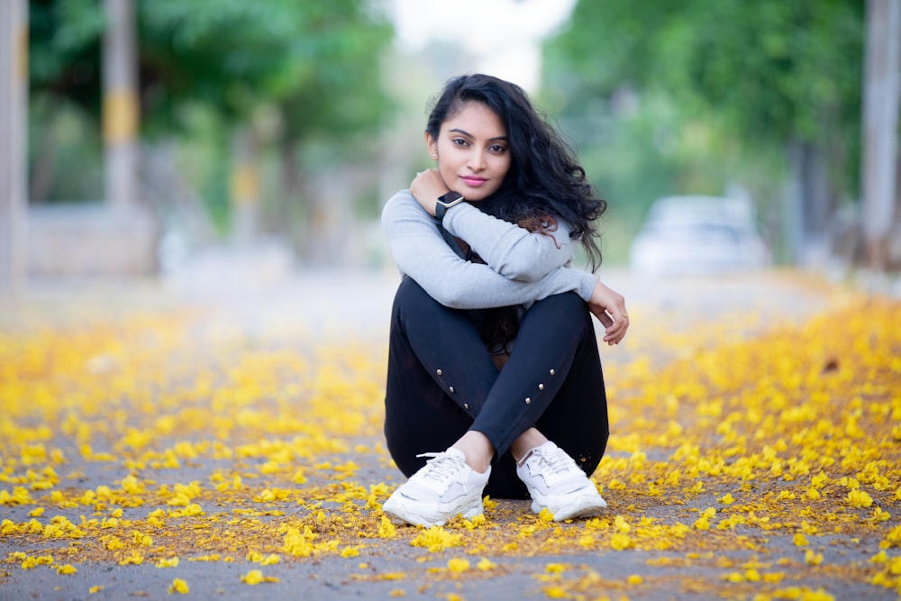 a woman sitting on the ground with yellow flowers all around her