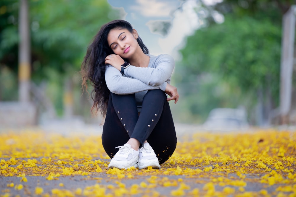 a woman sitting on the ground in a park