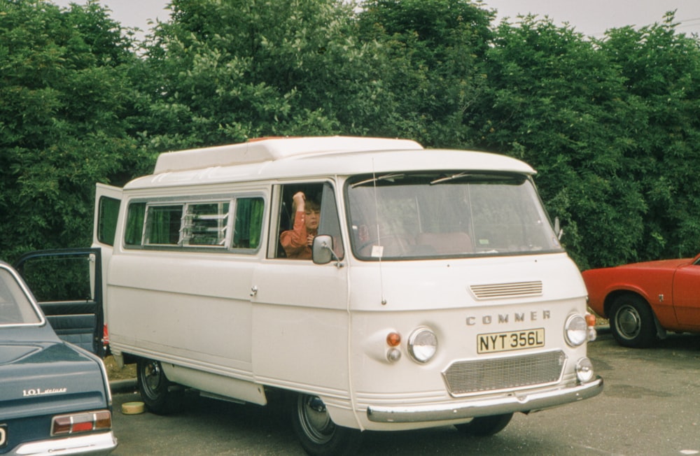 a white van parked in a parking lot next to other cars