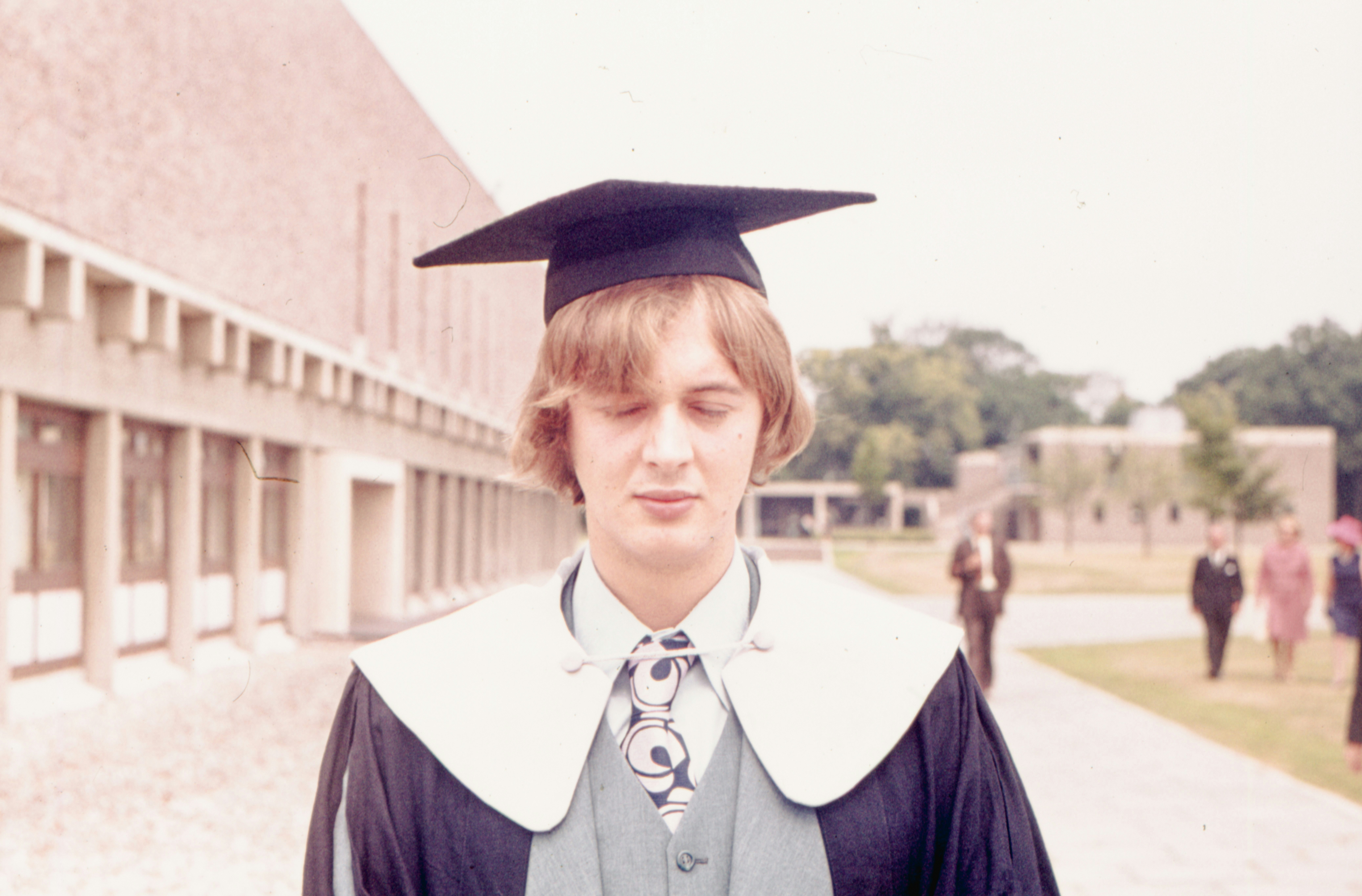 a young man wearing a graduation gown and a tie
