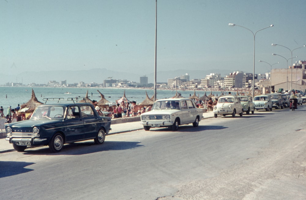 a line of cars driving down a street next to the ocean