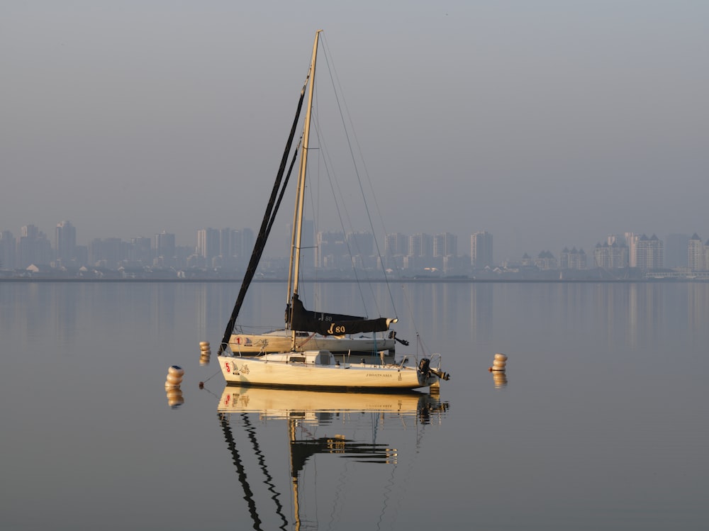 a sailboat in the water with a city in the background