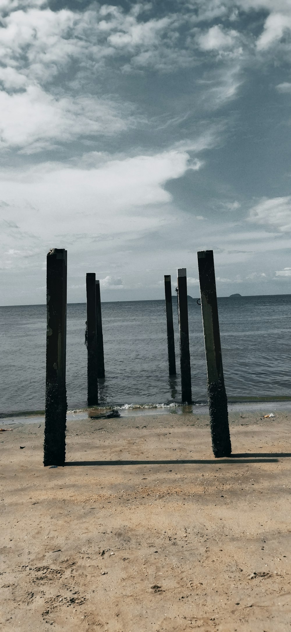 a row of wooden posts sitting on top of a sandy beach