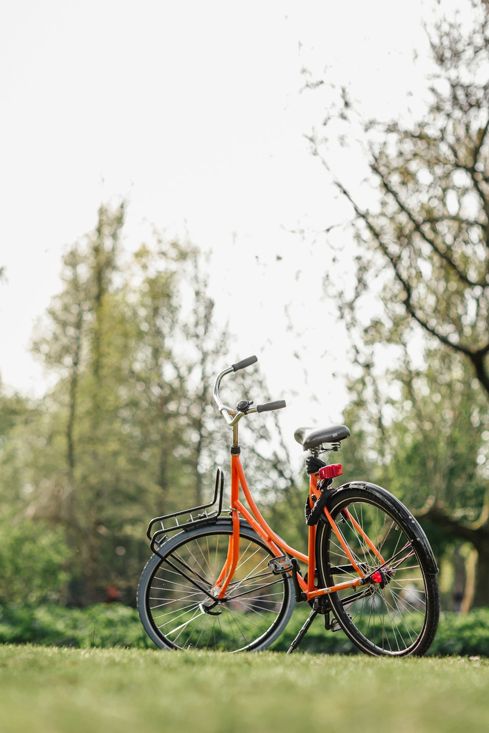 an orange bicycle is parked in the grass