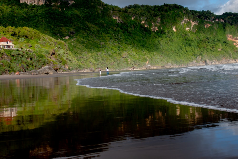 a couple of people standing on top of a beach near the ocean