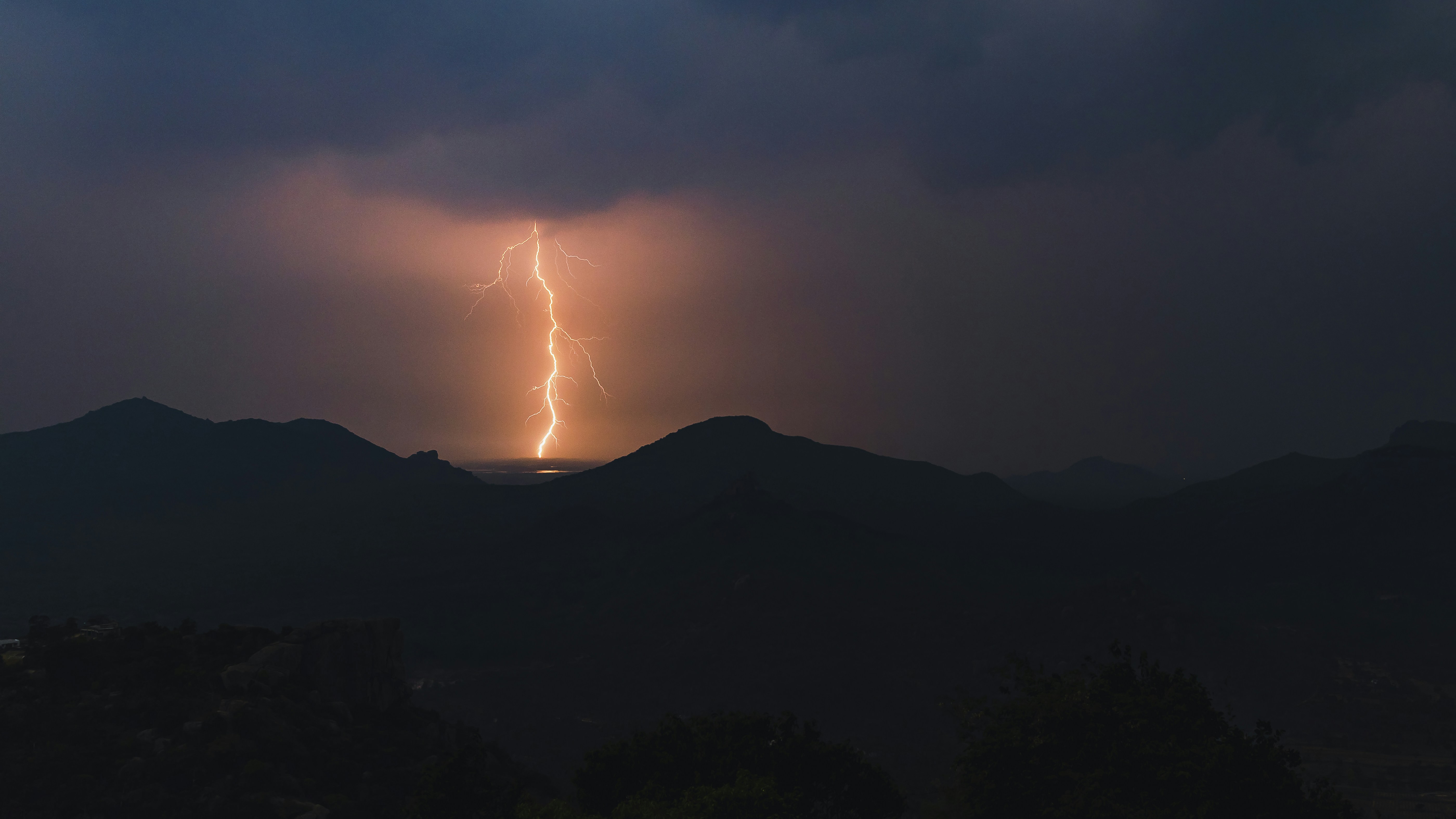 A lightning bolt is seen over a mountain range photo – Free Lightning ...