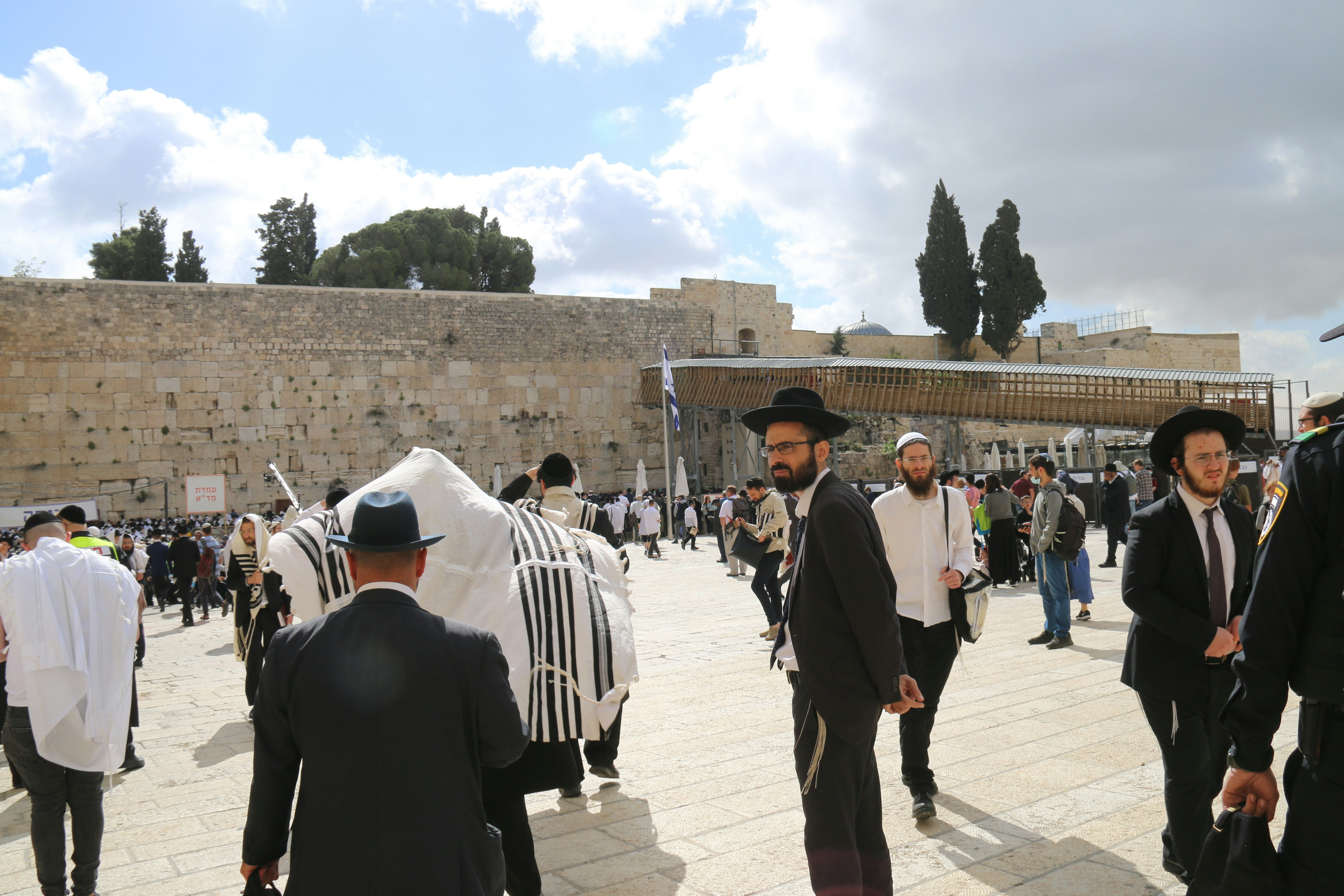 a group of men in jewish garb standing in front of a stone wall