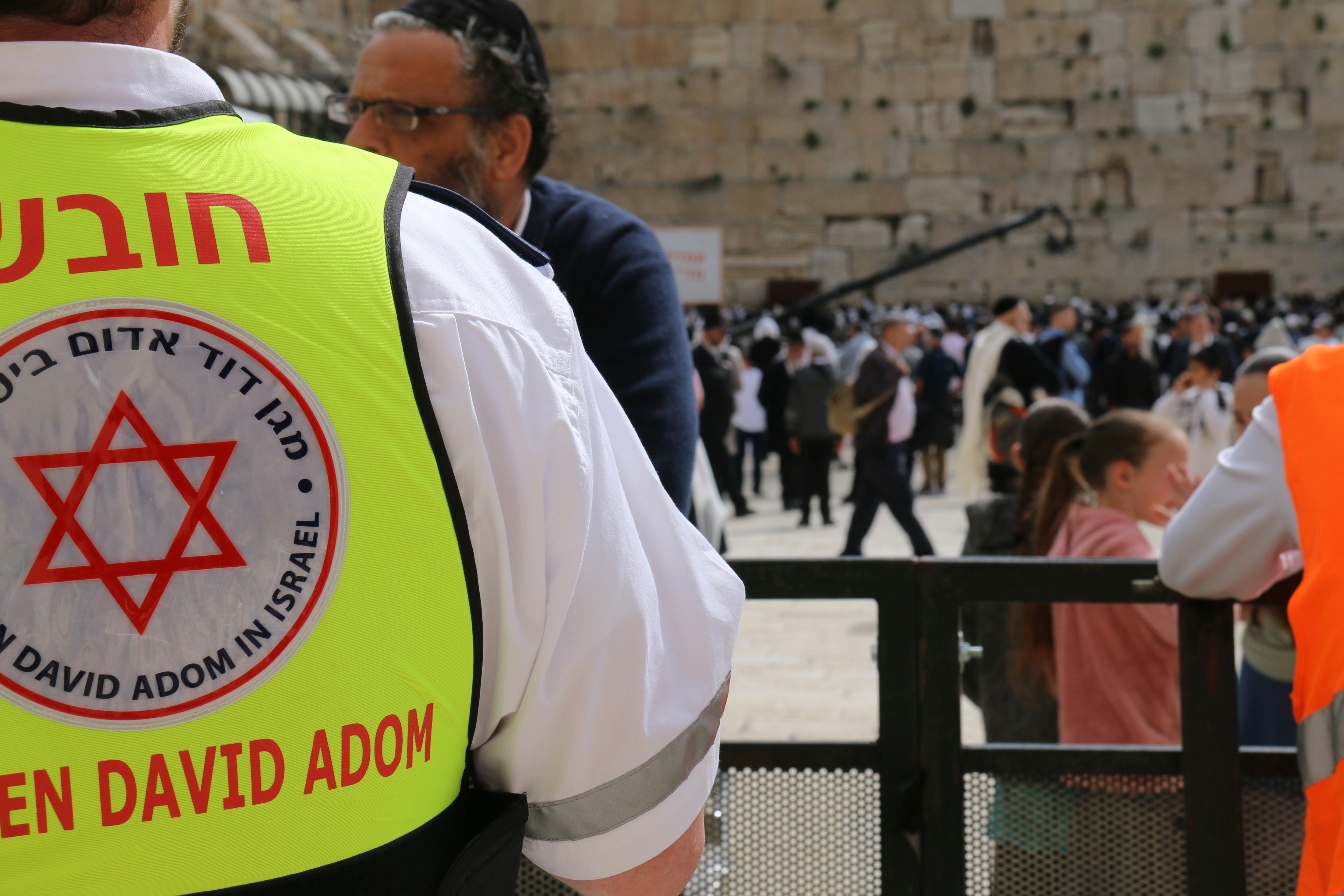 a man in a yellow vest standing in front of a crowd of people