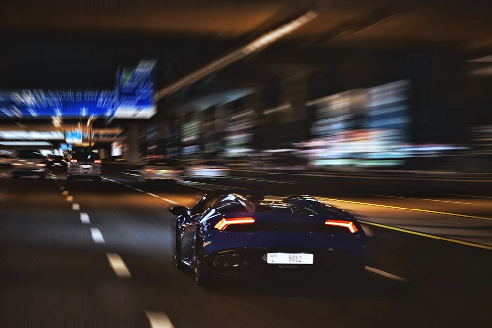 a blue sports car driving down a city street