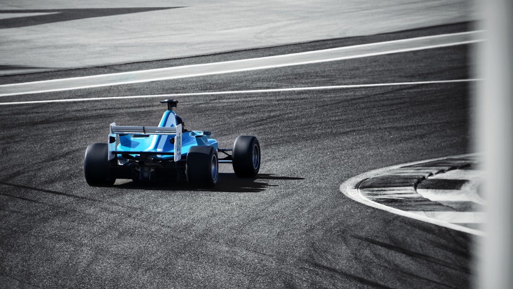 a blue race car driving down a race track