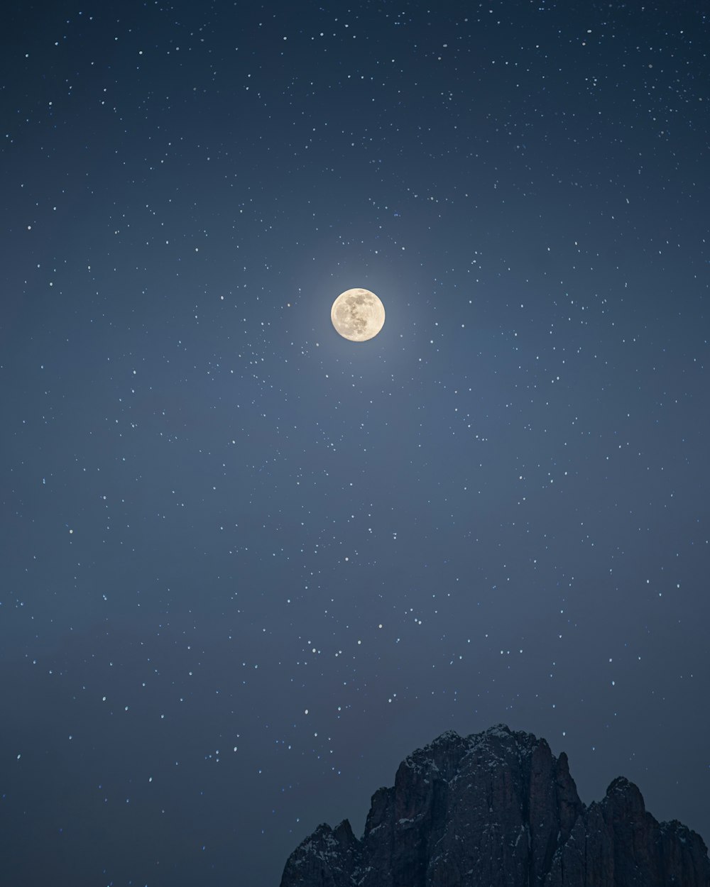 a full moon is seen above a mountain range