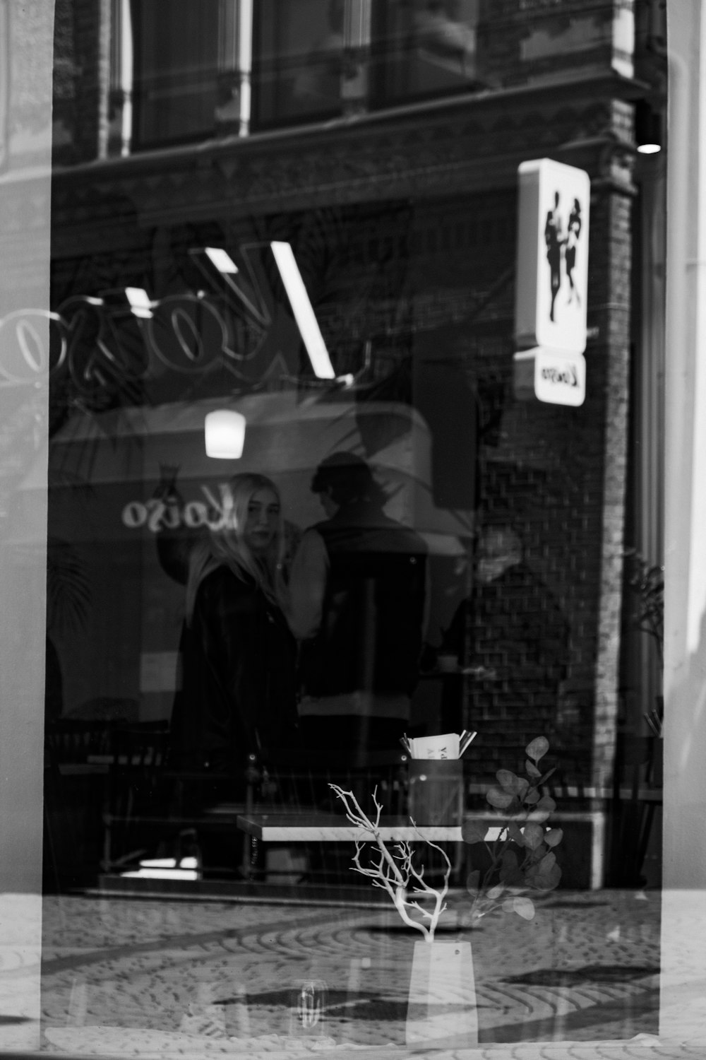 a black and white photo of a man sitting in a window