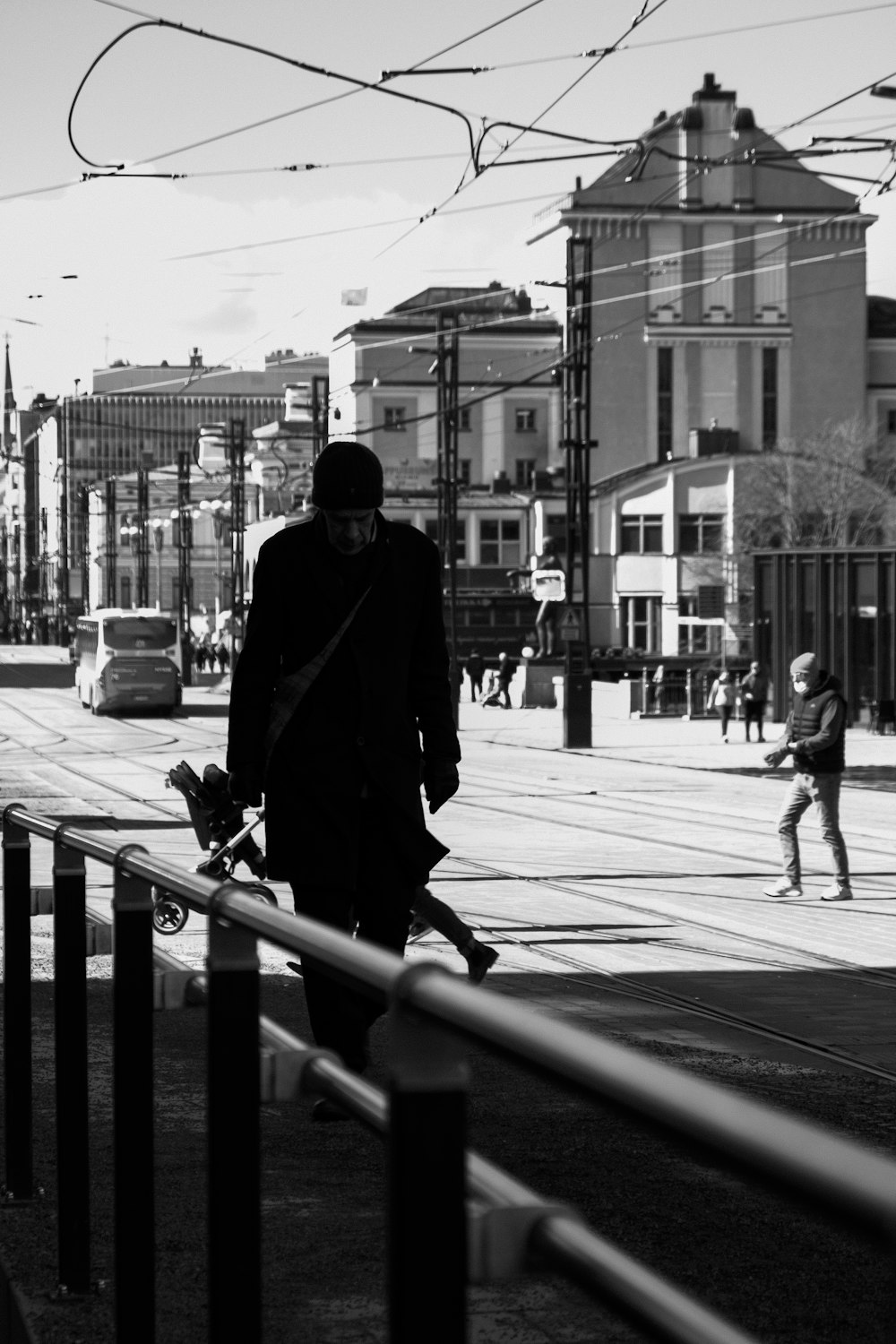 a man walking down a street holding a skateboard