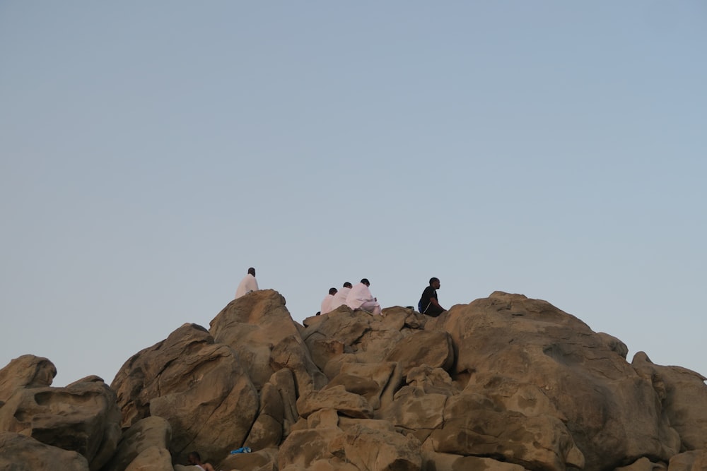 a group of people sitting on top of a large rock