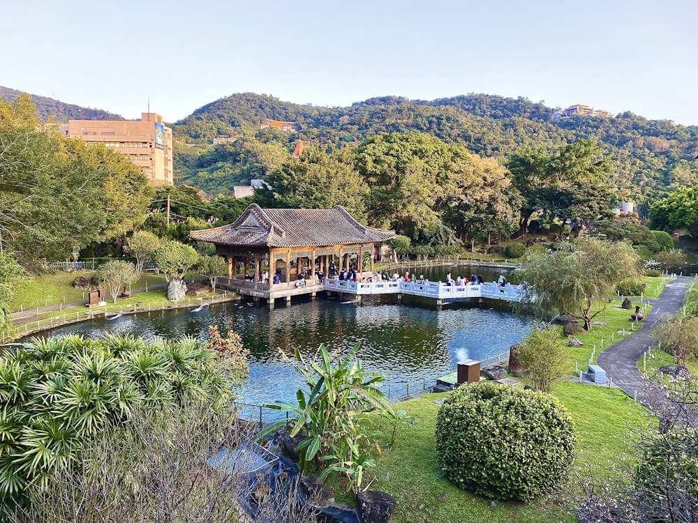 a lake surrounded by lush green trees and a pavilion