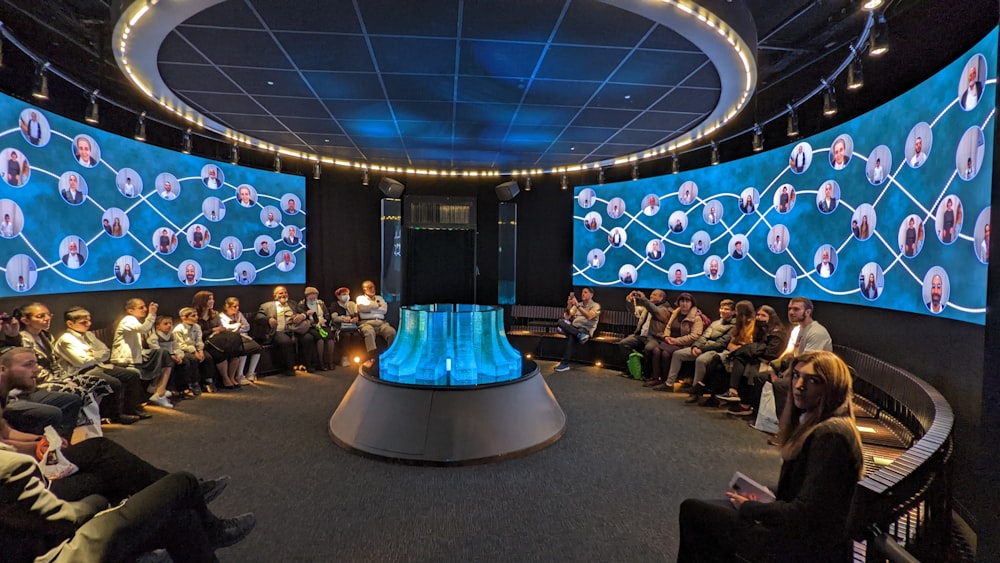 a group of people sitting in front of a large screen