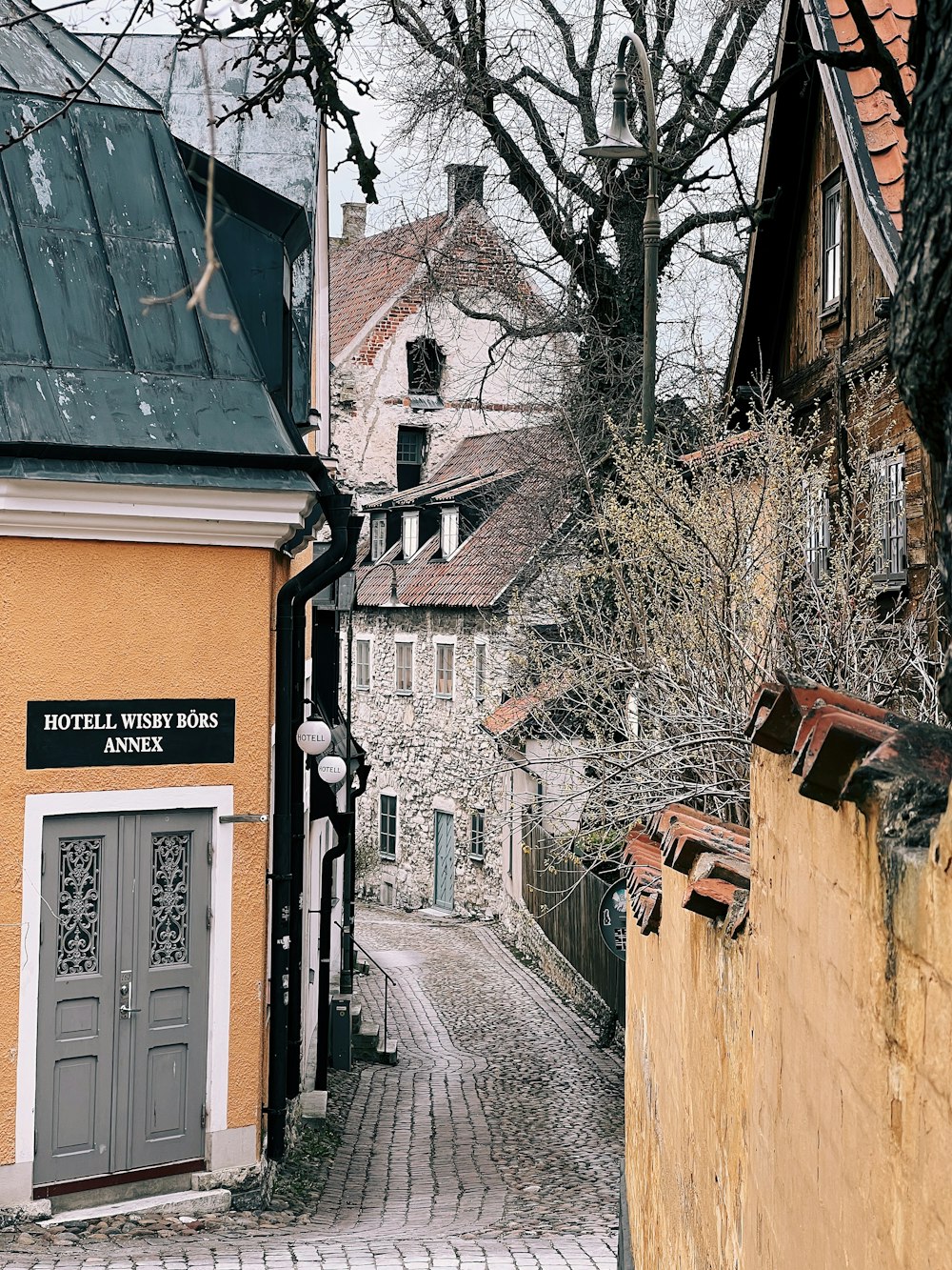 a cobblestone street with a yellow building and a clock tower in the background