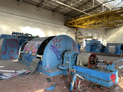 Modern factory interior with workers applying vibrant blue and yellow paint on walls.