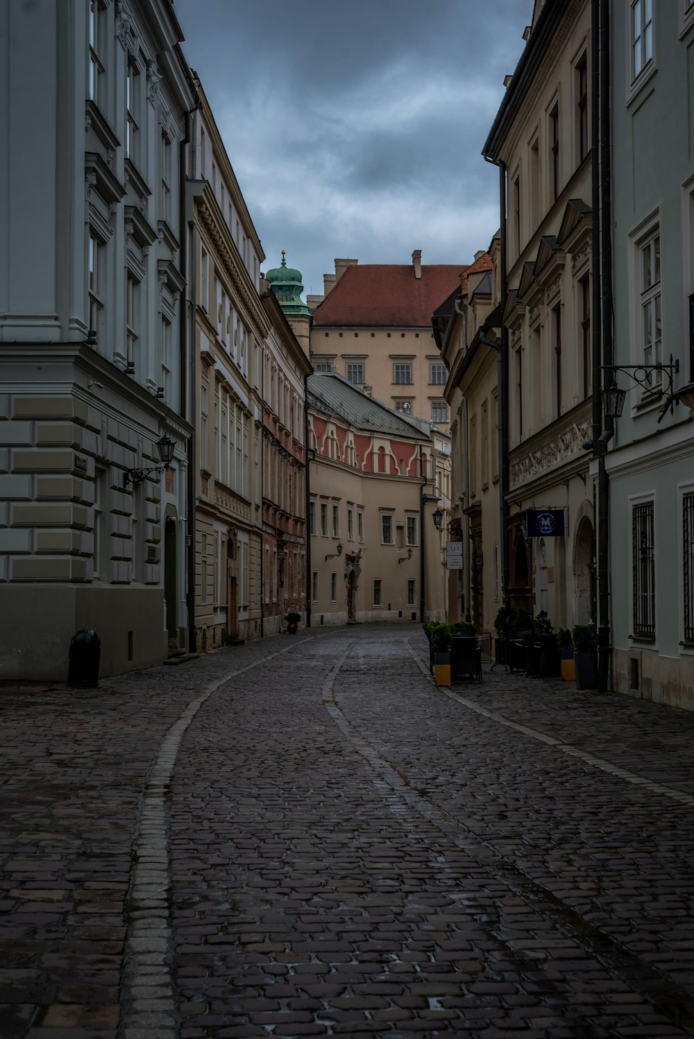 a cobblestone street lined with buildings under a cloudy sky